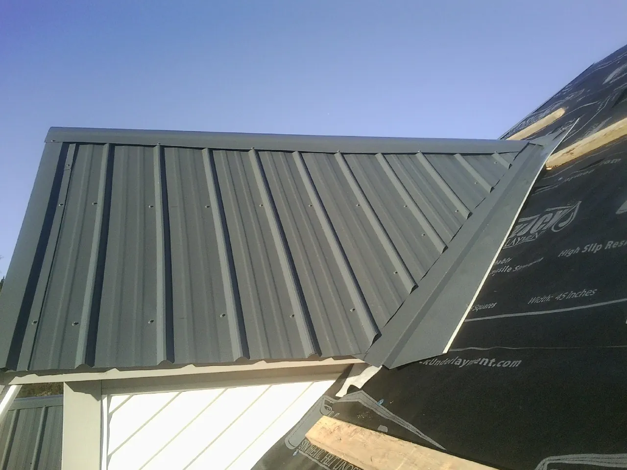Gray metal roof panels going on over a garage gable in Ordway