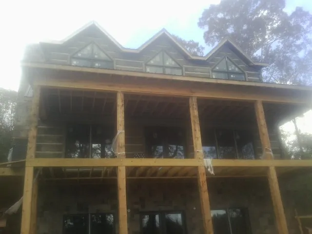 Dormers and porch framing on a large log home under construction — Roof Coating work by our crew in Ordway