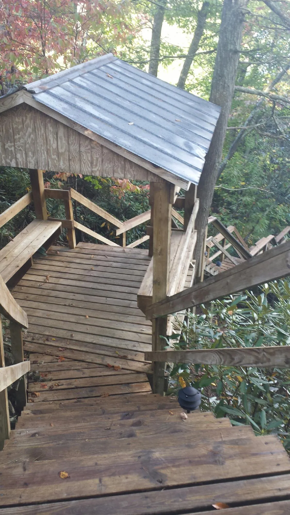 Metal roofed shelter over wooden steps on a wooded walkway — Skylight Repair & Installation work by our crew in Ordway