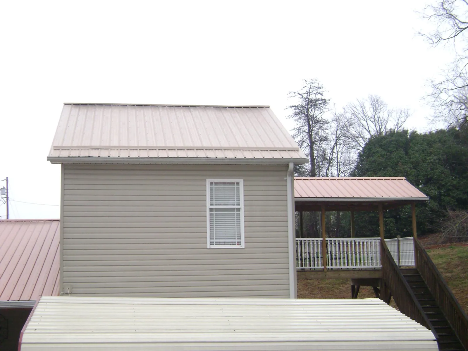 Tan metal roofs on a two story addition and attached porch, from a Roof Replacement job in Ordway