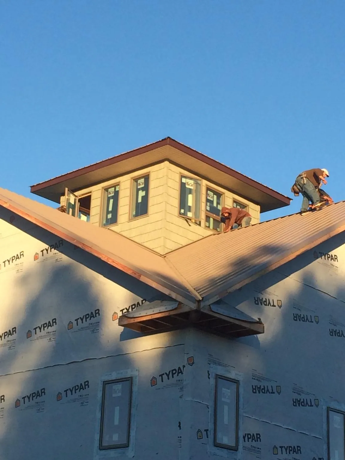 Roofers working around a rooftop cupola on a new metal roof at sunset — Roof Waterproofing in Ordway by Roofing Brothers
